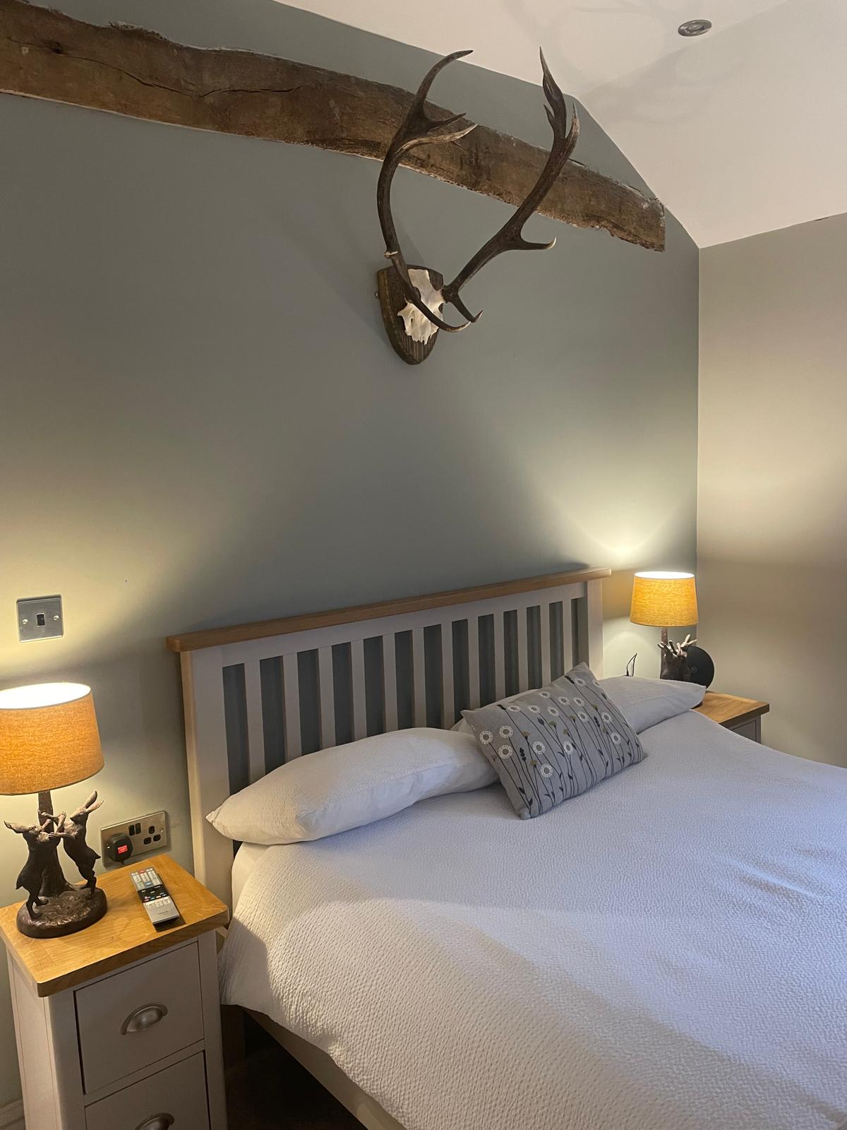 The Retreat — guest bedroom with oak beams and mounted antlers