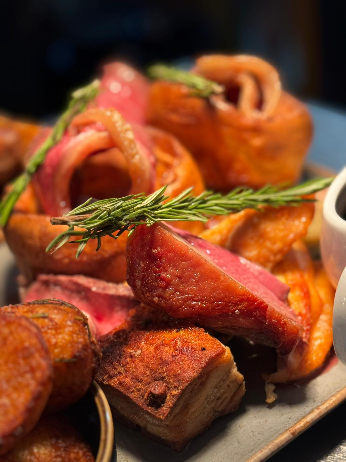 Close-up of the Sunday roast, beef and pork belly with rosemary